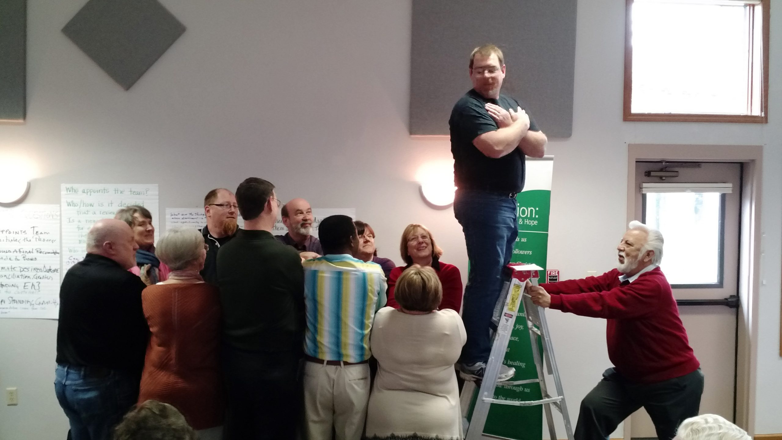 Rodger Schmell, representing Eastern District Conference, prepares for a “trust fall” into the arms of fellow Constituency Leaders Council (CLC) members representing multiple theological perspectives across the denomination during the CLC’s March 2016 meeting. Lupe Aguilar, representing South Central Mennonite Conference, holds the ladder. (Photo by Janie Beck Kreider)