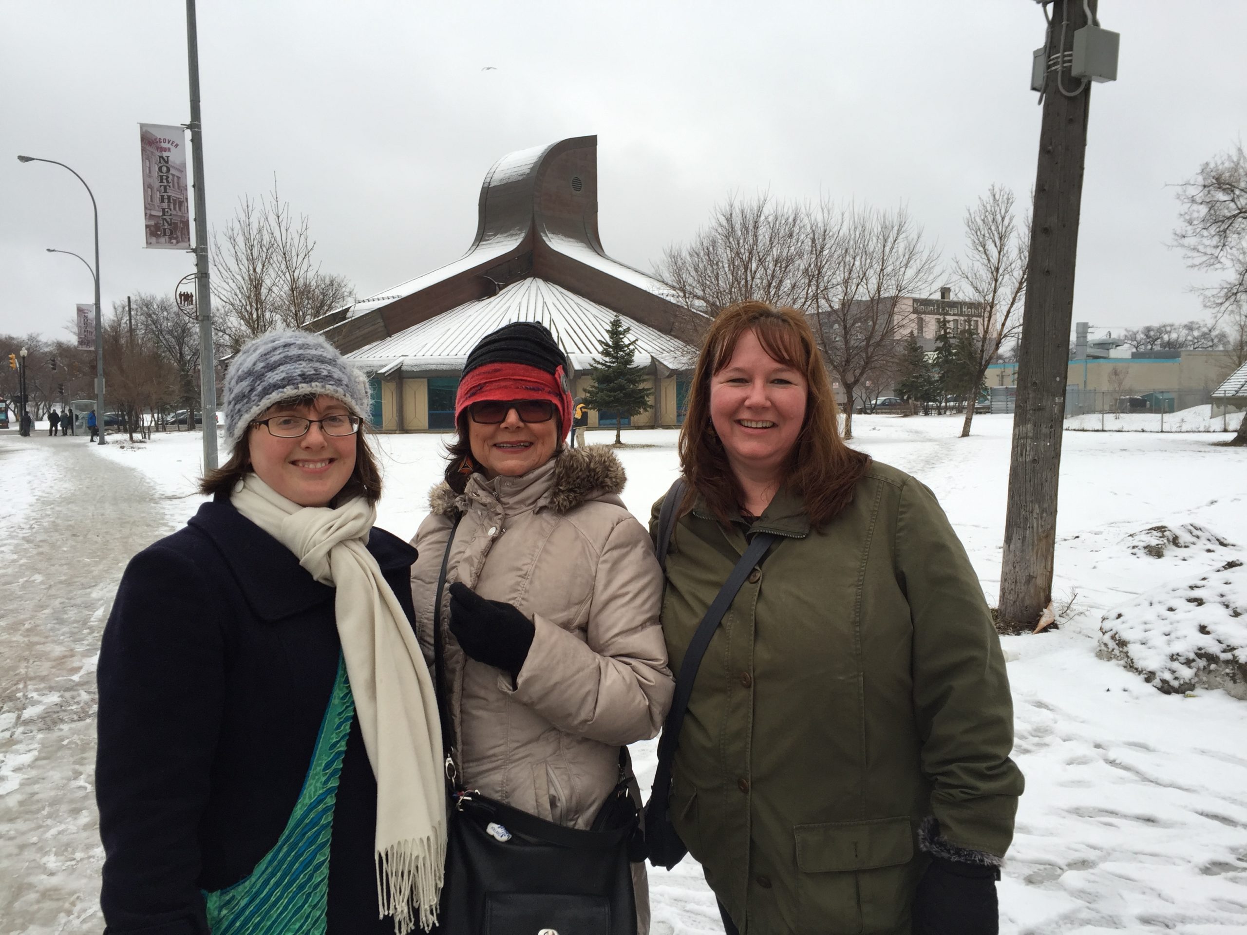 (izq. a der.) Las representantes del Comité Central Menonita (CCM) Christina Dunfield (CCM Maritimes), Muriel Queval (CCM Quebec) y Dianne Climenhage (CCM Newfoundland Labrador) participaron de las reuniones sobre el impacto de la Doctrina del Descubrimiento el 5 y 6 de abril en la Casa Thunderbird de Winnipeg (fondo). (Foto provista por Erica Littlewolf/CCM)