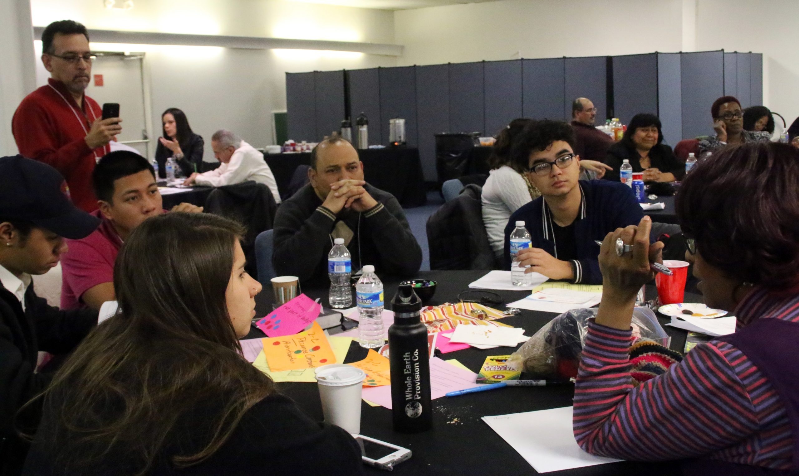 Los estudiantes menonitas de colegios universitarios fueron contribuyentes claves de los grupos de trabajo. (Alrededor de la mesa, desde adelante a la izquierda hacia la derecha) Gabby Castanon, de Goshen College (Indiana); Isaiah Crosby y Abe Mateo, de Hesston College (Kansas); Marvin Lorenzana, de la Red Menonita de Misión; Nashon Lora, de Goshen College; y Michelle Armster, de CCM. Fotografiando al grupo de trabajo aparece Gilberto Pérez, Jr., de Goshen College (de pie). (Foto de Carol Roth)