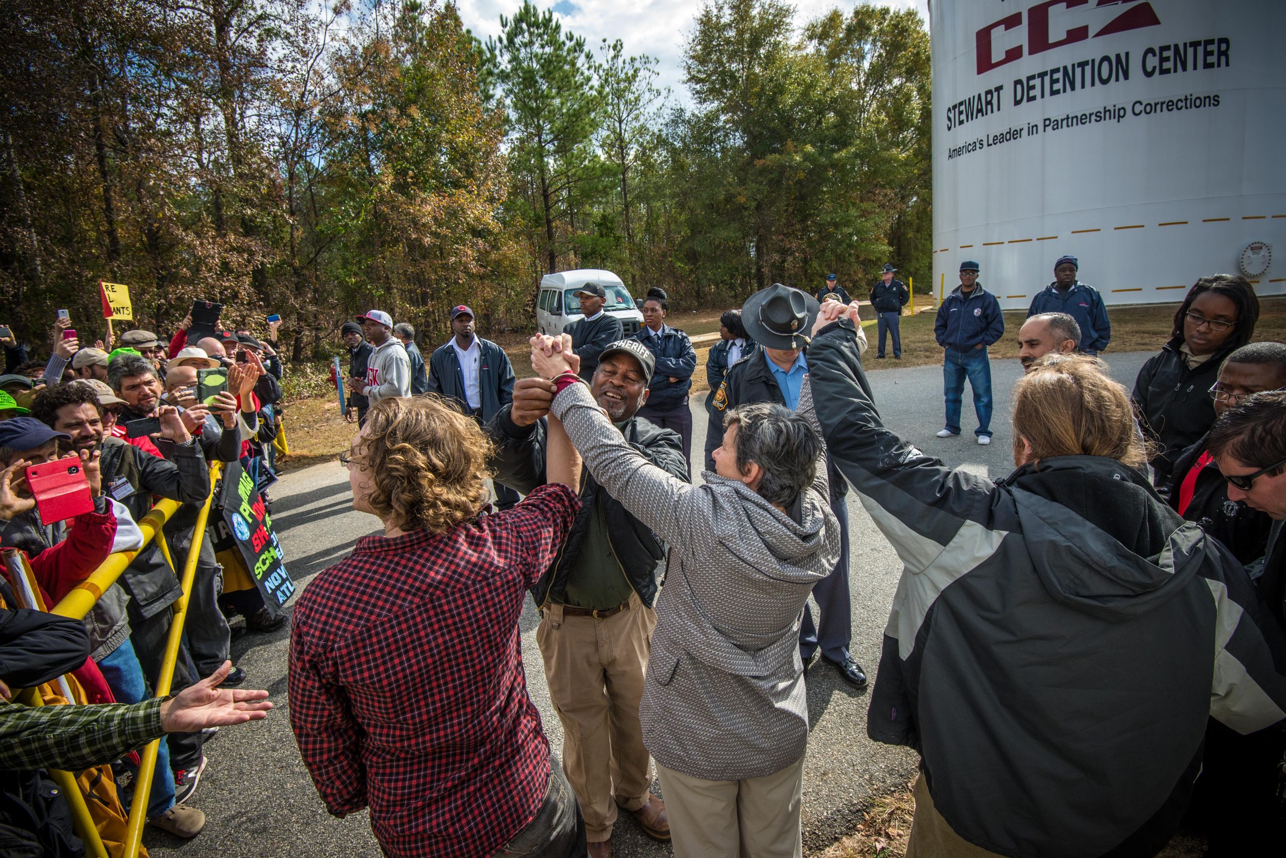 The “Stewart Five” raising their hands and singing We Shall Overcome as they are handcuffed and arrested for civil disobedience at Stewart Detention Center in Lumpkin, Ga., acting on their consciences for migrant justice.