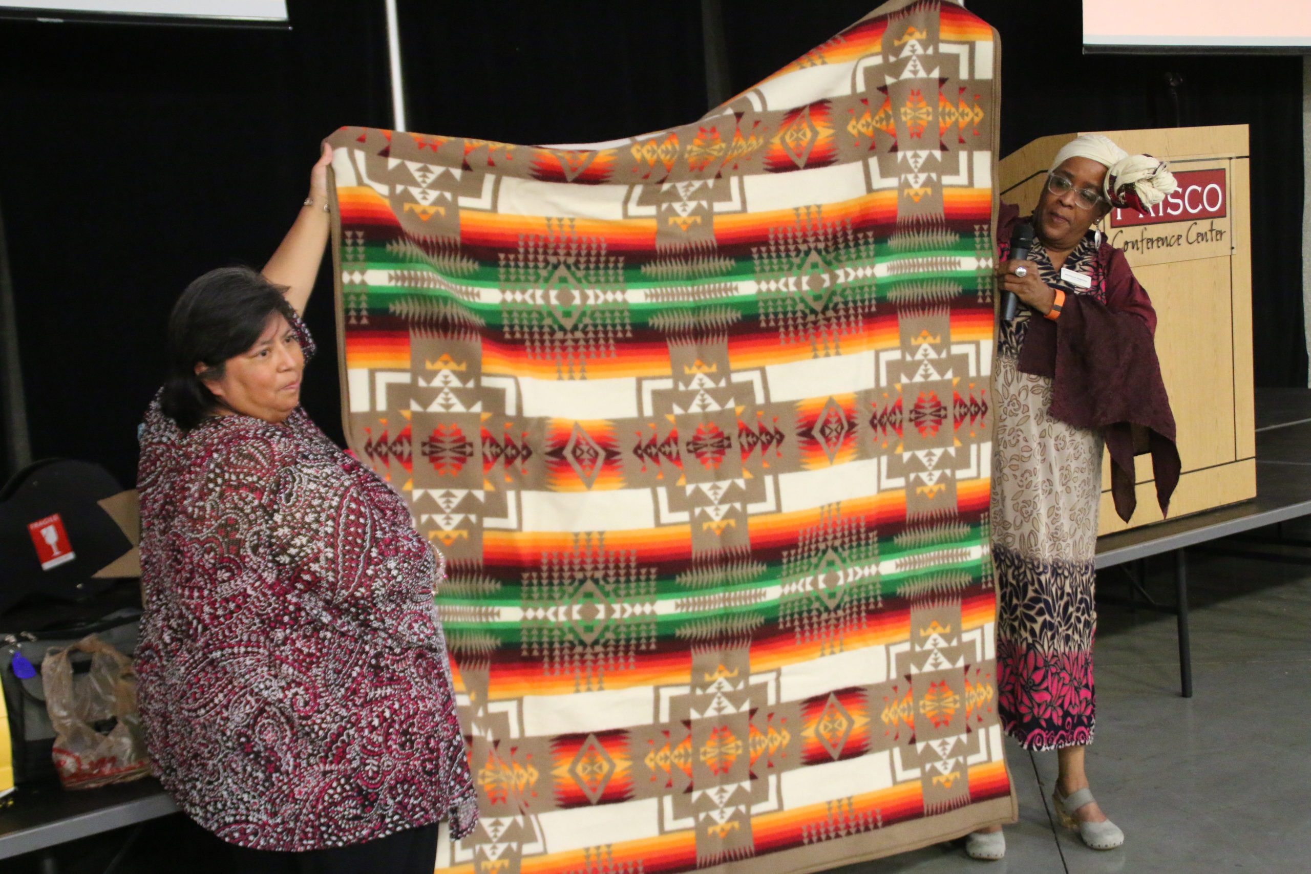 Carol Roth and Michelle Armster presenting Lawrence a Pendleton Blanket (Betty received a Cheyenne inspired quilt).