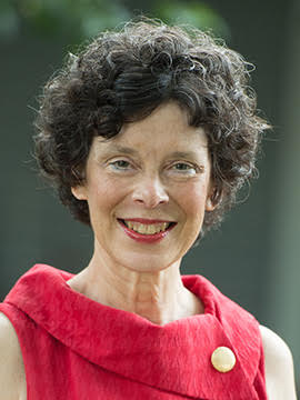 A middle-aged woman with short, curly brown hair, wearing a red blouse. 