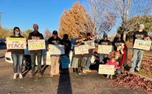 Ten protesters of all ages holding peace and anti-war signs.