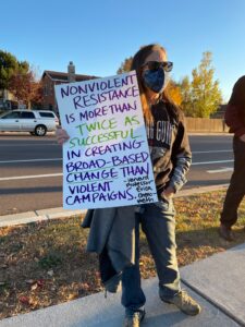 Female protestor holding sign that says "Nonviolent resistance is more than twice as successful in creating broad-based change than violent campaigns" 