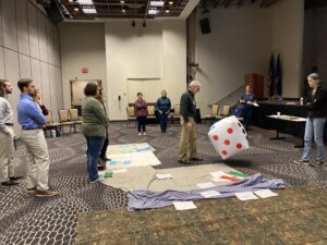 Educators participating in a game that involves a large blow-up die, with the "5" facing the camera.