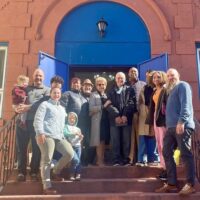 Group of 13 people on the doorstep of a church