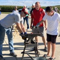 Joel Shenk helping an attendee forge gun pieces into something new. Photo by Nancy and Neal Beck.